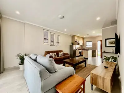 a living room with a couch and a table at Modern 2 Bedroom Apartment near Carstenhof Hospital, Glen Austin in Midrand