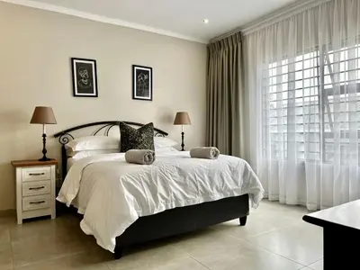a bedroom with a large bed and a window at Modern 2 Bedroom Apartment near Carstenhof Hospital, Glen Austin in Midrand