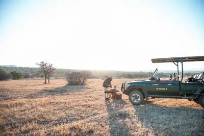a man standing next to a green truck in a field at Kwafubesi Tented Safari Camp in Mabula