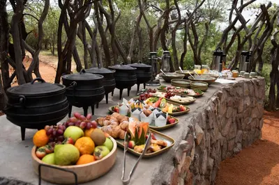 a table with many plates of food on it at Kwafubesi Tented Safari Camp in Mabula