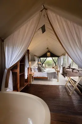 a bedroom in a tent with a bed and a tub at Kwafubesi Tented Safari Camp in Mabula