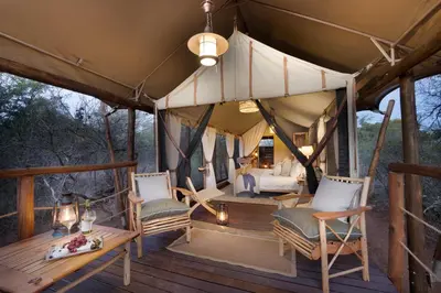 a room with chairs and a bed in a tent at Kwafubesi Tented Safari Camp in Mabula