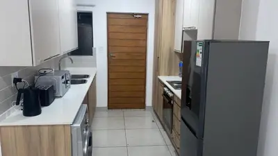 a kitchen with a refrigerator and a counter top at Spacious 2 bedroom, 2 bathroom unit in Pretoria