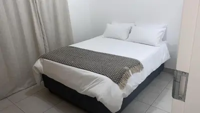 a bed with white sheets and pillows in a room at Spacious 2 bedroom, 2 bathroom unit in Pretoria