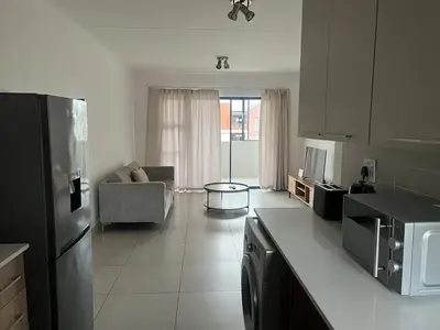a kitchen with a refrigerator and a living room at Spacious 2 bedroom, 2 bathroom unit in Pretoria