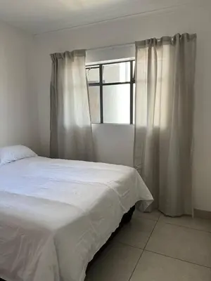 a bedroom with a white bed and a window at Spacious 2 bedroom, 2 bathroom unit in Pretoria