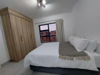 a bedroom with a white bed and a window at Spacious 2 bedroom, 2 bathroom unit in Pretoria
