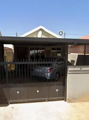 a fence with a car parked inside of a house at Sanctuary in Mahube Valley in Pretoria