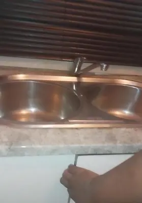 a metal sink in a kitchen with a persons hand at Sanctuary in Mahube Valley in Pretoria