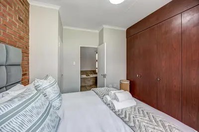 a bedroom with a large bed and a brick wall at Carlswald Escape in Midrand