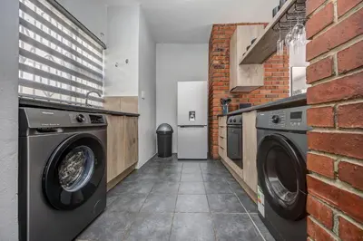 a laundry room with two washing machines and a brick wall at Carlswald Escape in Midrand