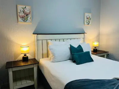 a bedroom with a white bed with two lamps on tables at Rugare Haven in Kempton Park