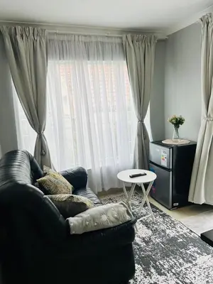 a living room with a black couch and a table at Rugare Haven in Kempton Park