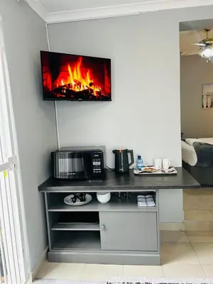 a kitchen with a microwave and a tv on a wall at Rugare Haven in Kempton Park
