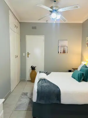 a bedroom with a bed and a ceiling fan at Rugare Haven in Kempton Park