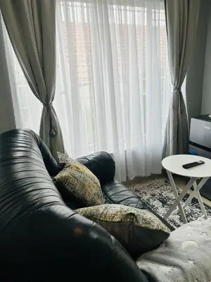 a couch with pillows sitting in front of a window at Rugare Haven in Kempton Park