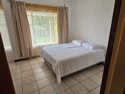 a bedroom with a bed and a window and a tiled floor at The comfort in Polokwane
