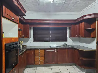 a large kitchen with wooden cabinets and a window at The comfort in Polokwane