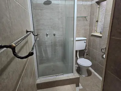 a bathroom with a toilet and a glass shower at The comfort in Polokwane