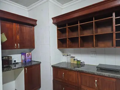 a kitchen with wooden cabinets and marble counter tops at The comfort in Polokwane