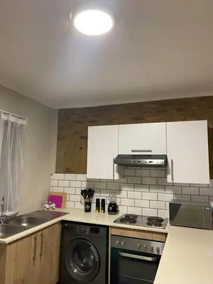 a kitchen with white cabinets and a washer and sink at Unmatched Stays in Kempton Park