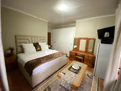 a bedroom with a large bed and a table at Kloofyard Guesthouse in Pretoria