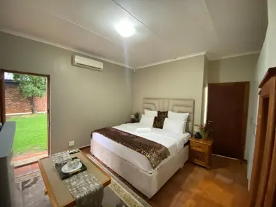 a bedroom with a large bed and a table at Kloofyard Guesthouse in Pretoria