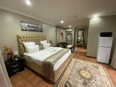 a bedroom with a large bed and a refrigerator at Kloofyard Guesthouse in Pretoria