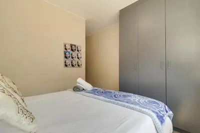 a bedroom with a white bed with a cabinet at Home Affairs by Waterfall in Midrand