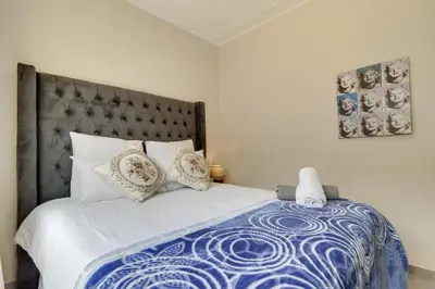 a bedroom with a blue and white bed with pillows at Home Affairs by Waterfall in Midrand