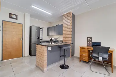 a kitchen with a counter and a refrigerator and a table at Home Affairs by Waterfall in Midrand