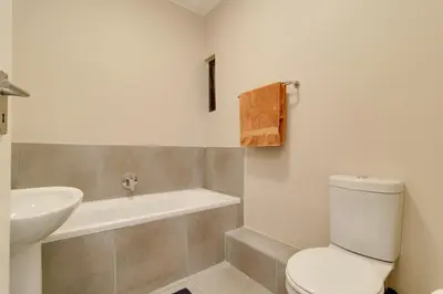a bathroom with a white toilet and a sink at Home Affairs by Waterfall in Midrand