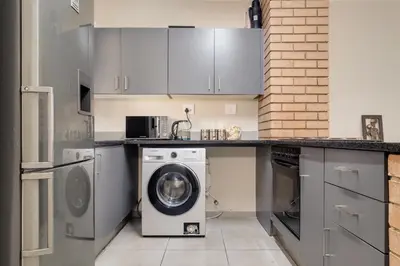 a kitchen with a washing machine and a washer at Home Affairs by Waterfall in Midrand