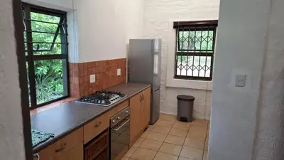 a kitchen with a stove and a sink and two windows at Lakeview Lodge in Hazyview
