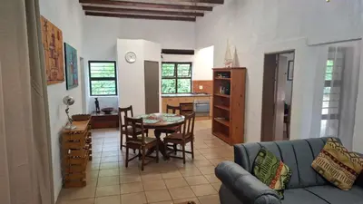 a living room with a table and chairs and a kitchen at Lakeview Lodge in Hazyview