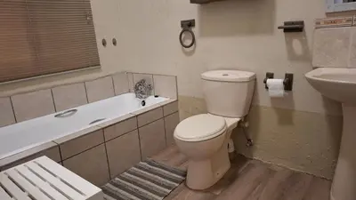 a bathroom with a toilet and a sink and a tub at Lakeview Lodge in Hazyview