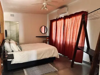 a bedroom with a bed and a red curtain at Warthog Wallow - Kruger National Park Phalaborwa in Phalaborwa