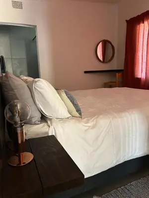 a bed with white sheets and pillows next to a table at Warthog Wallow - Kruger National Park Phalaborwa in Phalaborwa