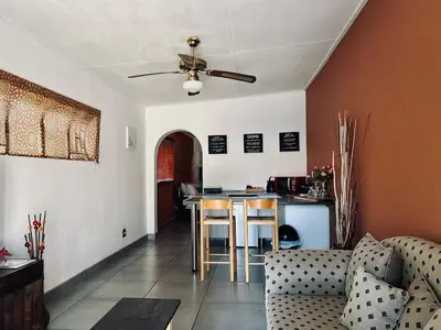 a living room with a ceiling fan and a kitchen at Warthog Wallow - Kruger National Park Phalaborwa in Phalaborwa