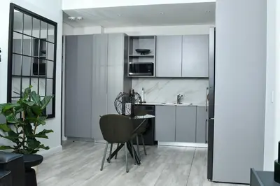 a kitchen with white cabinets and a table and a chair at 438 The Capital Trilogy in Pretoria