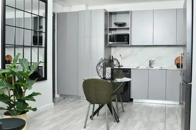 a kitchen with white cabinets and a table and chairs at 438 The Capital Trilogy in Pretoria