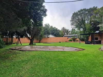 a grassy yard with a park with a tree at Buccleuch Home in Sandton