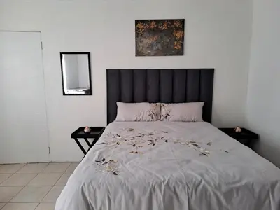 a bedroom with a large bed with a black headboard at Buccleuch Home in Sandton