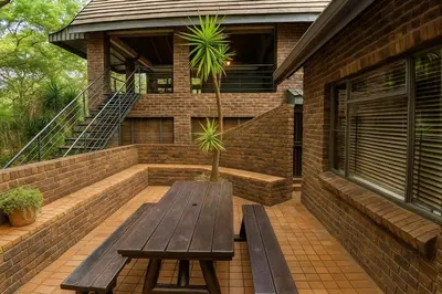 a wooden bench sitting on the patio of a house at Tree Lodge by My Adventure House in Marloth Park
