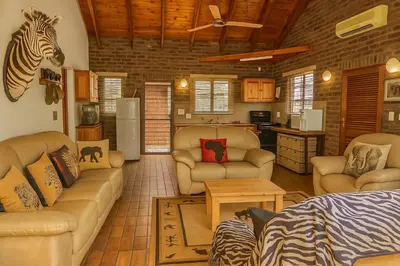 a living room with furniture and a zebra head on the wall at Tree Lodge by My Adventure House in Marloth Park