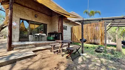 a wooden cabin with a picnic table and a grill at Figtree Escape in Marloth Park