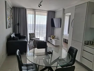 a living room with a glass table and chairs at Ellipse 1-Bedroom Lux Apartment in Midrand