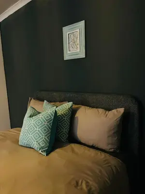 a bed with four pillows and a picture on the wall at Legae la rena in Polokwane