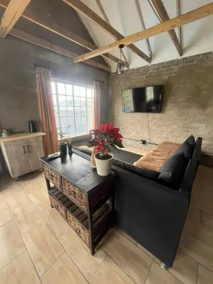 a living room with a black couch and a table at Kiewiets Nest Guesthouse in Pretoria