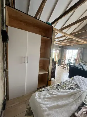 a bedroom with a bed and a white cabinet at Kiewiets Nest Guesthouse in Pretoria